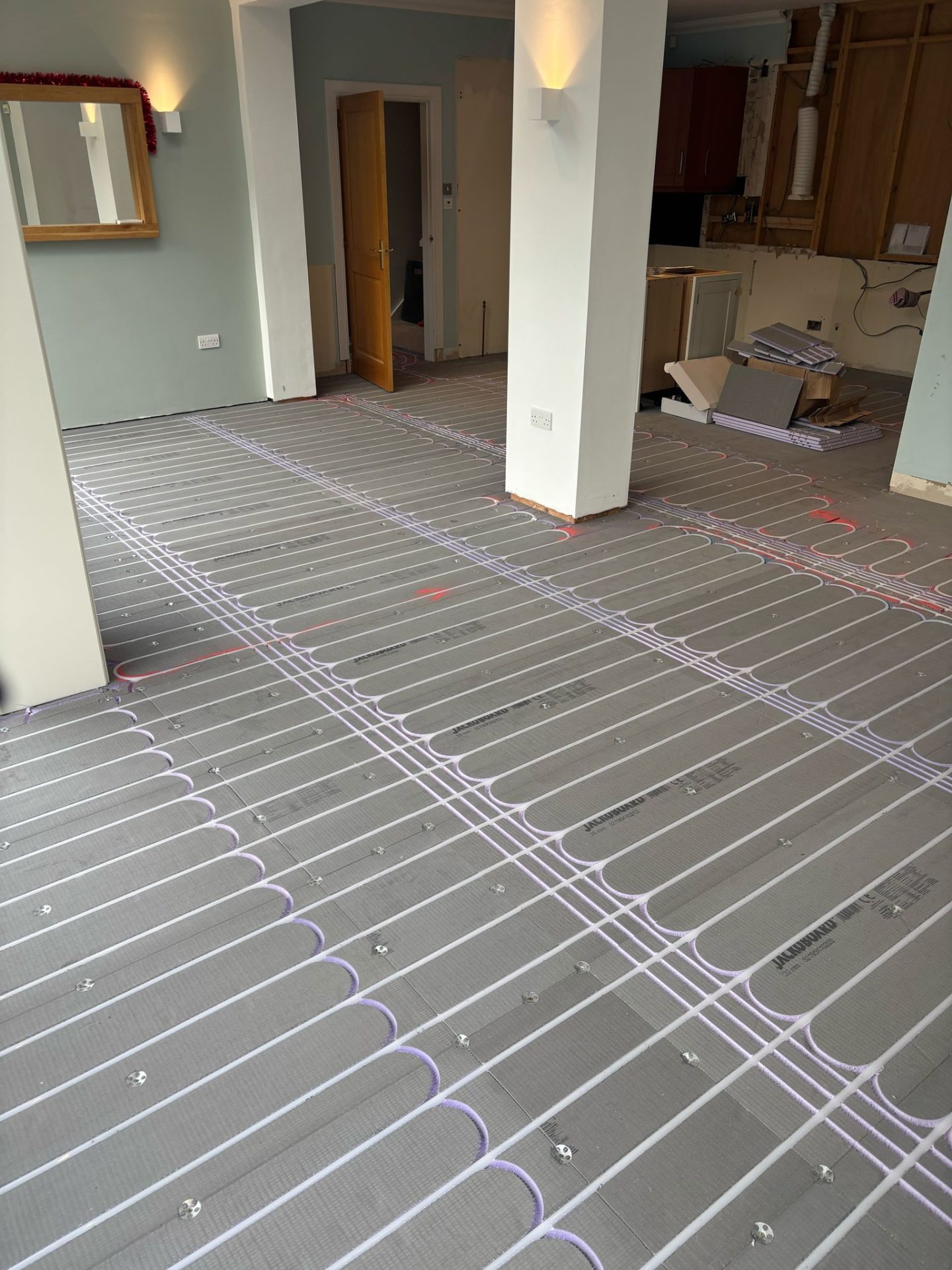 Retrofit underfloor heating pipes neatly installed in residential home renovation project.