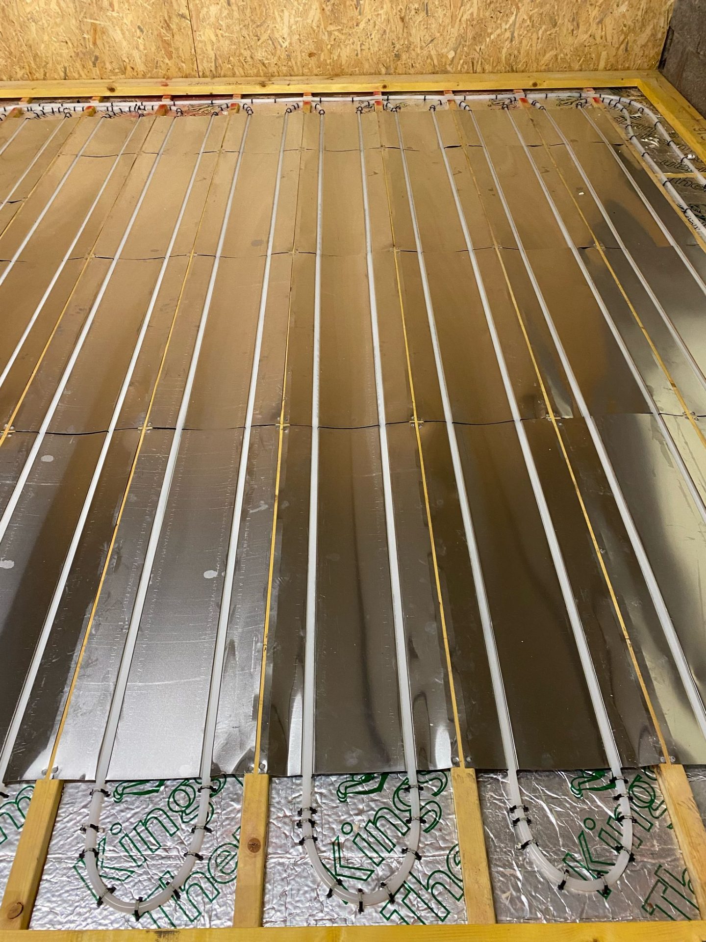 Retrofit underfloor heating on suspended timber floor. Pipes are laid out on the floor insulation.
